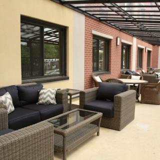 A modern outdoor patio with wicker furniture and a glass table on a terrace.