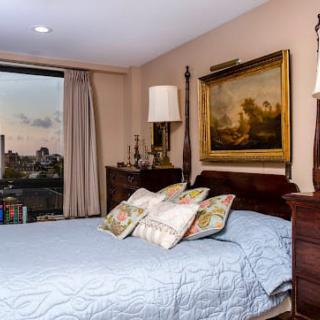 A cozy bedroom with elegant decor, featuring a large bed, decorative pillows, and a scenic window view.