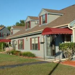A suburban home with red awnings and a well-maintained lawn.