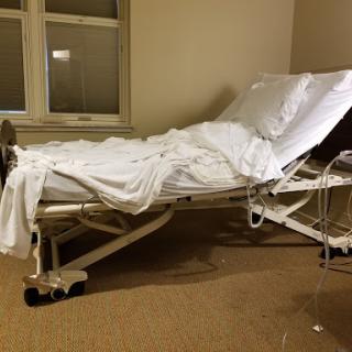 An empty hospital bed in a patient room, ready for use.