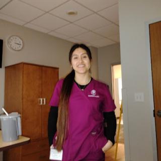 A healthcare professional in scrubs stands confidently in a hospital setting.