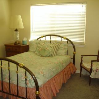 A cozy bedroom with a brass bed, bedside table, lamp, and window.