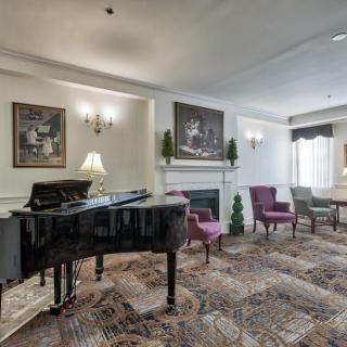 Elegant lounge area featuring a grand piano, comfortable seating, and tasteful artwork.