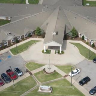 Aerial view of a large building with a circular driveway and adjacent parking lot.