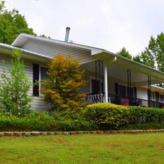 A cozy house with a spacious porch surrounded by lush greenery.