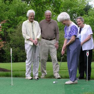 A group of seniors enjoying a day of putting on the golf course.
