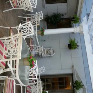 A cozy patio area with white metal chairs and tables, accented by potted plants and decor.