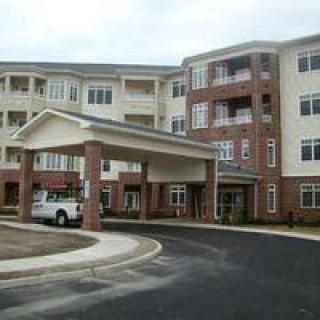 A multi-story residential building with a covered entrance and a car parked in the driveway.