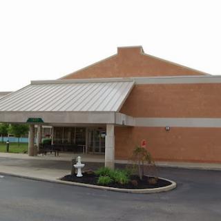 A modern brick building featuring a covered entrance and landscaped surroundings.