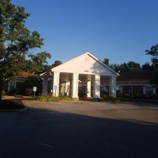 A peaceful hotel entrance bathed in morning sunlight, surrounded by greenery.