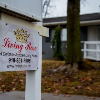 A 'Living Rose' real estate sign stands in front of a residential property.