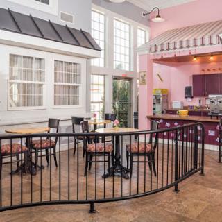 A charming cafe interior featuring a mix of dining tables and a bar area, illuminated by natural light.