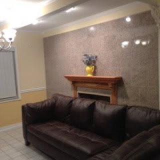 A cozy living room with a dark sofa and a decorated fireplace.