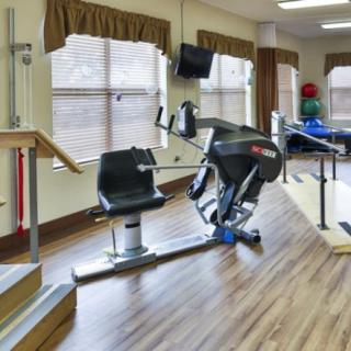A rehabilitation room equipped with exercise machines and parallel bars.