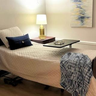 A cozy and modern bedroom with a neatly made bed, stylish lamp, and decorative art on the wall.