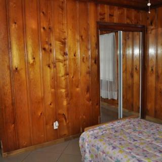 A cozy bedroom with wood-paneled walls and a mirrored closet door.