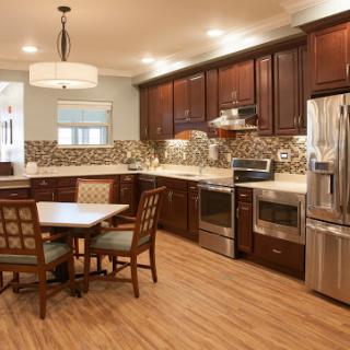 A modern kitchen featuring wooden cabinets, sleek appliances, and a cozy dining area.