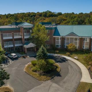 Aerial view of a building with a circular driveway surrounded by trees.