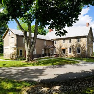 A charming stone house surrounded by lush greenery and a clear blue sky.