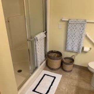 A tidy bathroom with a shower, towels, and storage baskets.