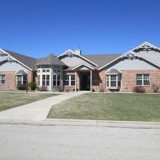 A single-story brick house with a well-maintained front yard in a suburban neighborhood.