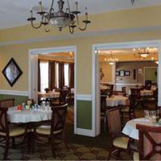 A cozy restaurant interior with elegantly set tables and chandeliers.