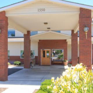 The entrance of a brick building with columns and surrounding landscaping.