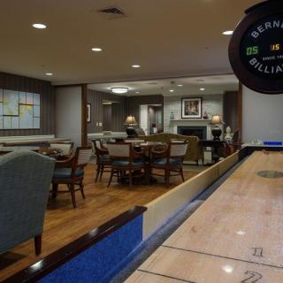 A cozy game room featuring a shuffleboard table and comfortable seating.