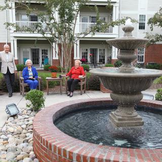 Seniors enjoying a peaceful afternoon in a courtyard garden with a fountain.