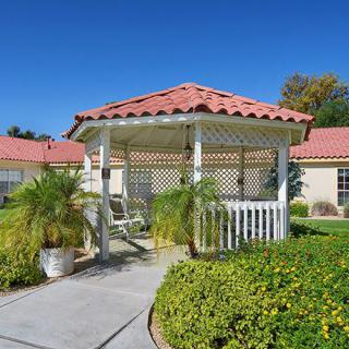 A charming gazebo in a sunny garden setting.