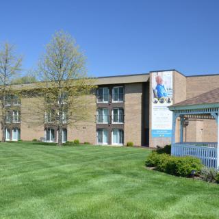 A college building with a well-maintained lawn and a gazebo.