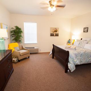 A cozy bedroom with elegant decor, featuring a comfortable bed, a plush chair, and soft lighting.