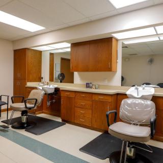Interior view of a barbershop with chairs and mirrors along the counter.