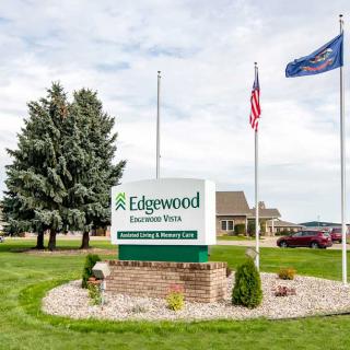 Outdoor sign for Edgewood, accompanied by flags nearby.