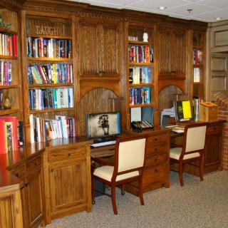 A cozy library with wooden bookshelves, computers, and seating for study.