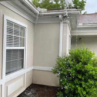 A view of the corner of a house featuring a window and nearby bush.
