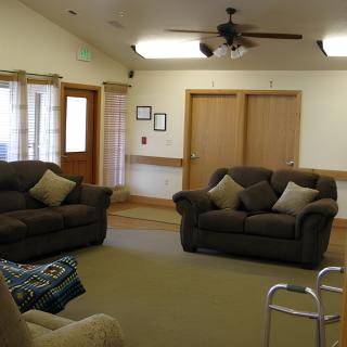 A cozy living room with two sofas, a ceiling fan, and wooden doors.