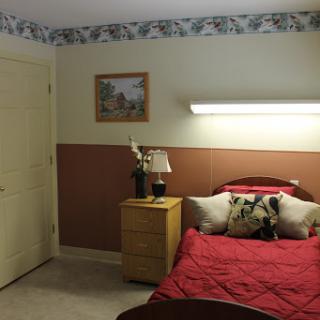 A cozy bedroom featuring a red bedspread, decorative pillows, and a warm ambiance.