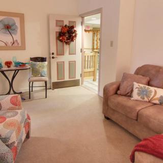 A cozy living room with colorful decor and a comfortable sofa, featuring an autumn-themed wreath on the door.