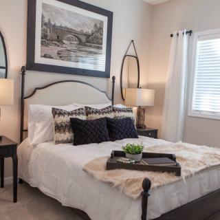 A modern bedroom with a neatly made bed, decorative pillows, and stylish lamps.