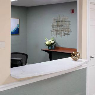 A neatly arranged reception area with a desk, decorative flowers, and wall art.
