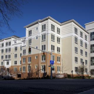 A multi-story residential apartment building under a clear blue sky.