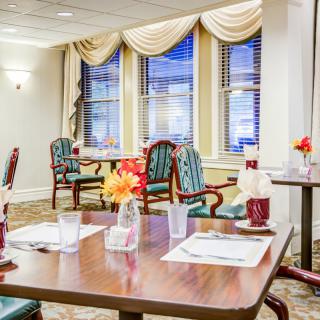 A well-appointed dining room with neatly arranged tables and chairs, adorned with colorful flowers and elegant curtains.