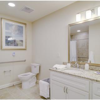 A modern bathroom with a sink, mirror, toilet, and decorative artwork.