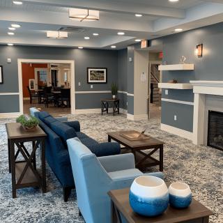 A modern living room with blue walls, comfortable seating, and a cozy fireplace.