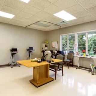 A well-lit therapy room designed for rehabilitation sessions, featuring a central table and therapy equipment.