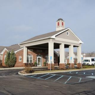 A building with a portico entrance and an adjacent parking area.