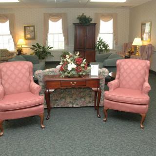 A cozy living room with two pink armchairs, a wooden coffee table, and various plants for decoration.