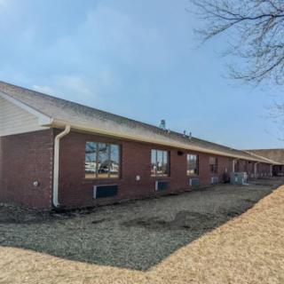 A one-story brick building with several windows and a sloped roof.
