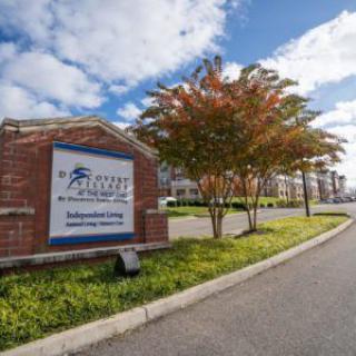 Entrance to an apartment complex with a clear sky and trees lining the road.